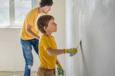 Oğluyla evde tamirat yapan bir adam, çocuklara ellerinde bir spatulayla duvarları alçılamayı öğretiyor.