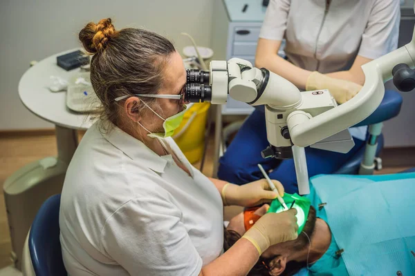 Лечение зубов с помощью микроскопа. Мужчина с зубами осмотрен у дантиста. Запись к дантисту. стиль жизни, реальная жизнь — стоковое фото
