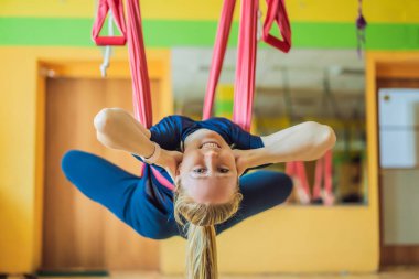 Genç ve güzel bir kadın spor salonunda hava yogası yapıyor. Yaşam biçimi
