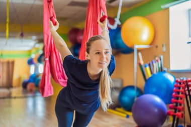 Genç ve güzel bir kadın spor salonunda hava yogası yapıyor. Yaşam biçimi