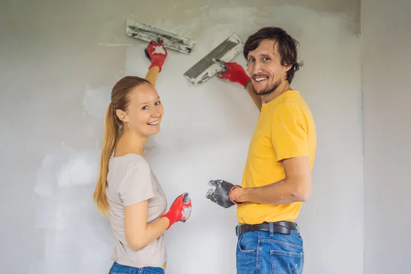 Bir adam ve bir kadın evin duvarlarını alçılıyor. DIY Ev Yenilemesi — Stok fotoğraf