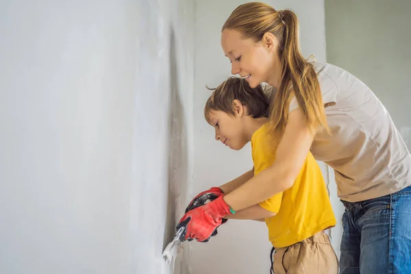 Köylü oğlu olan kadın evde tamirat yapıyor. Çocuğa elinde spatulayla duvarları sıva yapmayı öğretiyor. — Stok fotoğraf