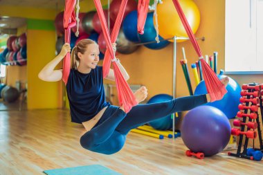 Genç ve güzel bir kadın spor salonunda hava yogası yapıyor. Yaşam biçimi.