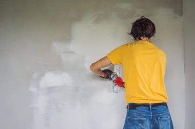 Sıvacı ev iyileştirme ustası macun bıçağıyla apartman duvarını doldurmaya çalışıyor.