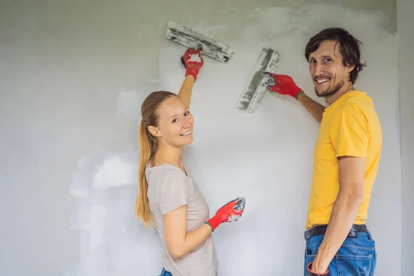 Un uomo e una donna stanno intonacando i muri della casa. Ristrutturazione casa fai da te — Foto Stock