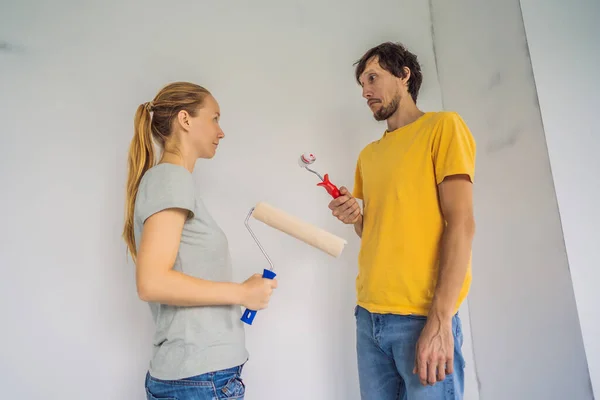 A man and a woman with rollers for painting the walls. A man with a very small bolster, symbolizing a small penis. renovation diy paint couple in new home painting wall — Foto Stock
