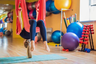 Genç ve güzel bir kadın spor salonunda hava yogası yapıyor. Yaşam biçimi