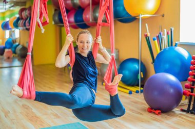 Genç ve güzel bir kadın spor salonunda hava yogası yapıyor. Yaşam biçimi
