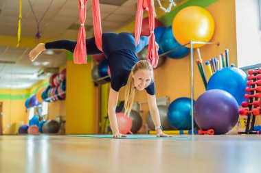Genç ve güzel bir kadın spor salonunda hava yogası yapıyor. Yaşam biçimi