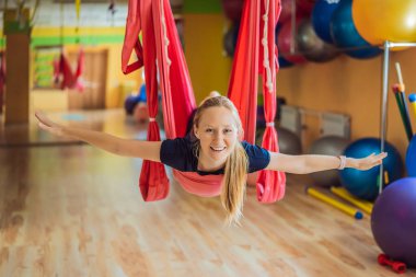 Genç ve güzel bir kadın spor salonunda hava yogası yapıyor. Yaşam biçimi