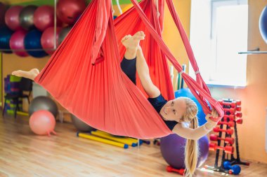 Genç ve güzel bir kadın spor salonunda hava yogası yapıyor. Yaşam biçimi