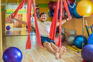 Spor salonunda hava yogası yapan genç bir adam. Yaşam biçimi