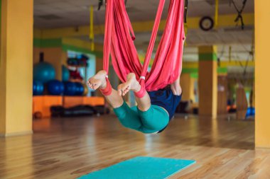 Yetişkin bir kadın stüdyoda hamakla anti-yerçekimi yogası yapıyor. Yaşam biçimi