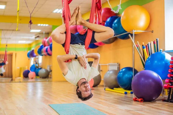 Spor salonunda hava yogası yapan genç bir adam. Yaşam biçimi