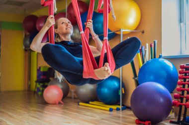 Genç ve güzel bir kadın spor salonunda hava yogası yapıyor. Yaşam biçimi