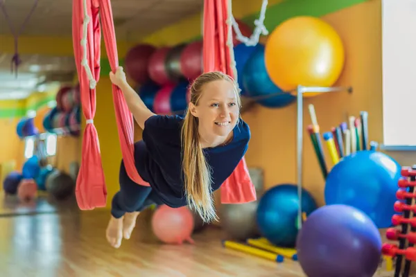 Genç ve güzel bir kadın spor salonunda hava yogası yapıyor. Yaşam biçimi