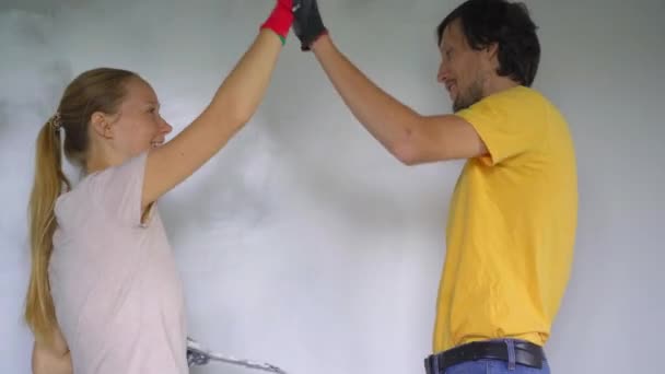 Un hombre y una mujer jóvenes están renovando sus paredes en su casa. Están aplicando masilla a la pared. Haga la renovación usted mismo — Vídeos de Stock