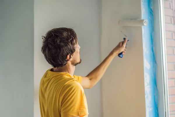 Ein männlicher Hausmaler arbeitet beim Streichen und Grundieren der Wand mit einer Malerrolle. Heimwerken — Stockfoto