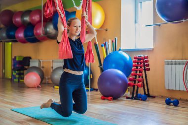Genç ve güzel bir kadın spor salonunda hava yogası yapıyor. Yaşam biçimi