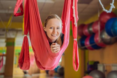 Genç ve güzel bir kadın spor salonunda hava yogası yapıyor. Yaşam biçimi