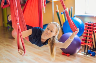Genç ve güzel bir kadın spor salonunda hava yogası yapıyor. Yaşam biçimi
