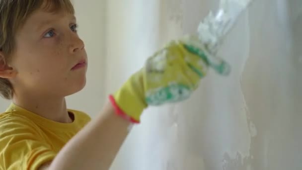 一个年轻人和他的儿子正在他们家整修墙壁。他们正在把油灰涂在墙上.你自己改造一下吧教孩子们如何自己修理 — 图库视频影像
