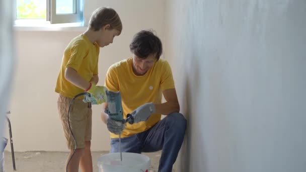 Een jongeman en zijn zoon doen een renovatie in hun huis. Ze brengen klei aan op de muur. Maak zelf een renovatie. Kinderen leren om zelf reparaties uit te voeren — Stockvideo