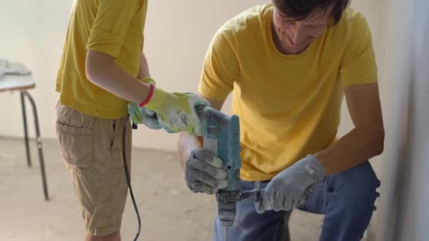 Молодий чоловік і його син роблять ремонт стін у своєму будинку. Вони змішують шпаклівку з ручним дрилем. Зробив ремонт сам. Навчання дітей робити ремонт самостійно — стокове відео