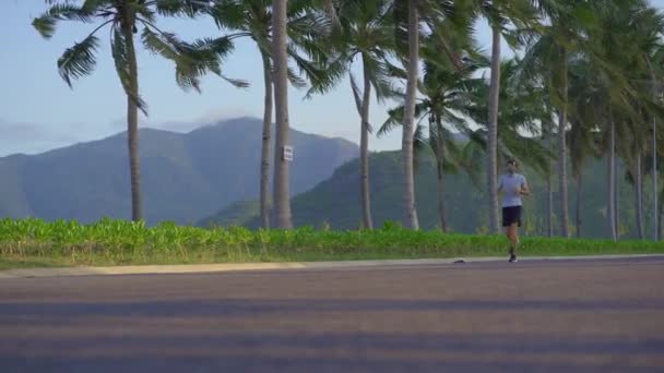 Um homem com uma máscara facial corre numa rua num ambiente tropical.. — Vídeo de Stock