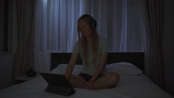 Une femme la nuit allume une méditation, application de relaxation sur sa tablette pour se détendre avant d'aller au lit. Applications anti-stress. Mode de vie sain. Nouvelle normalité — Video