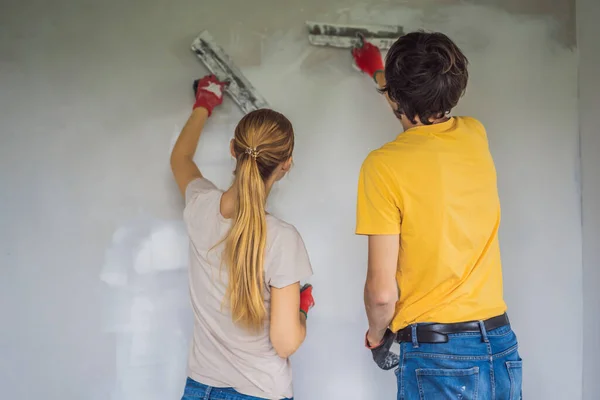 Egy férfi és egy nő vakolják a ház falait. DIY házfelújítás — Stock Fotó