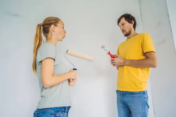 A man and a woman with rollers for painting the walls. A man with a very small bolster, symbolizing a small penis. renovation diy paint couple in new home painting wall — Foto Stock