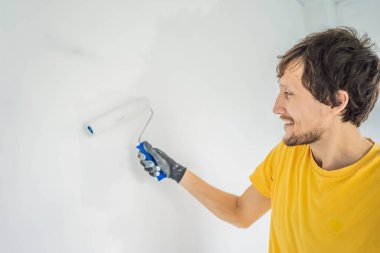 Bir erkek boyacı boyacı boya ve boya silindiriyle duvar astar. ÇEVİR
