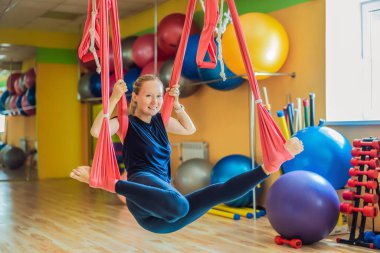 Genç ve güzel bir kadın spor salonunda hava yogası yapıyor. Yaşam biçimi
