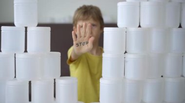 Elinde harf durağı olan bir çocuk plastik kutulardan yapılmış bir duvarla kırılıyor. Plastik kirliliğini durdurun. Tek kullanımlık plastikleri azaltın. Yavaş çekim videosu
