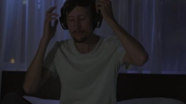 Geceleri bir adam uyumadan önce dinlenmek için meditasyon ve telefonuna rahatlama uygulaması açar. Stres önleyici uygulamalar. Sağlıklı bir yaşam tarzı. Yeni normal