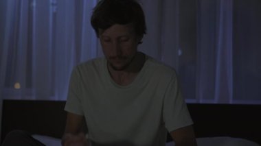 Geceleri bir adam uyumadan önce dinlenmek için meditasyon ve telefonuna rahatlama uygulaması açar. Stres önleyici uygulamalar. Sağlıklı bir yaşam tarzı. Yeni normal