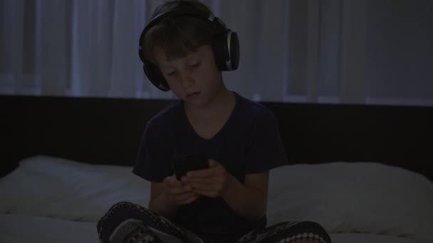 Un garçon la nuit allume une méditation, application de relaxation sur son téléphone pour se détendre avant d'aller au lit. Applications anti-stress. Mode de vie sain. Nouvelle normalité — Video