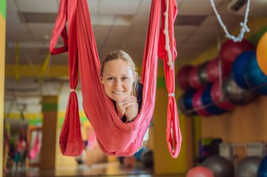 Genç ve güzel bir kadın spor salonunda hava yogası yapıyor. Yaşam biçimi