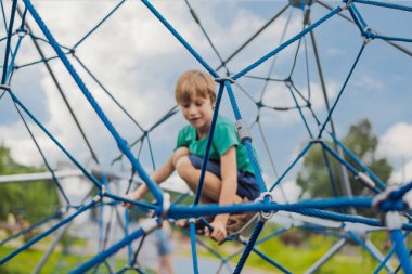 Çocuk oyun bahçesinde ipe tırmanıyor.