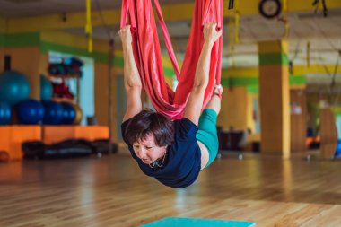 Yetişkin bir kadın stüdyoda hamakla anti-yerçekimi yogası yapıyor. Yaşam biçimi