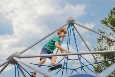 Çocuk oyun bahçesinde ipe tırmanıyor.