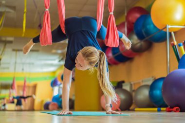 Genç ve güzel bir kadın spor salonunda hava yogası yapıyor. Yaşam biçimi
