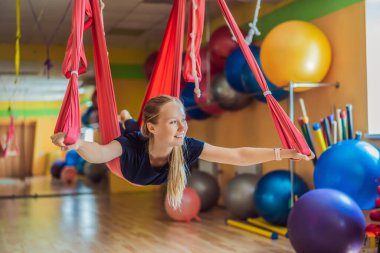 Genç ve güzel bir kadın spor salonunda hava yogası yapıyor. Yaşam biçimi