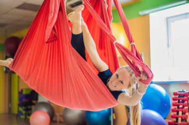 Genç ve güzel bir kadın spor salonunda hava yogası yapıyor. Yaşam biçimi