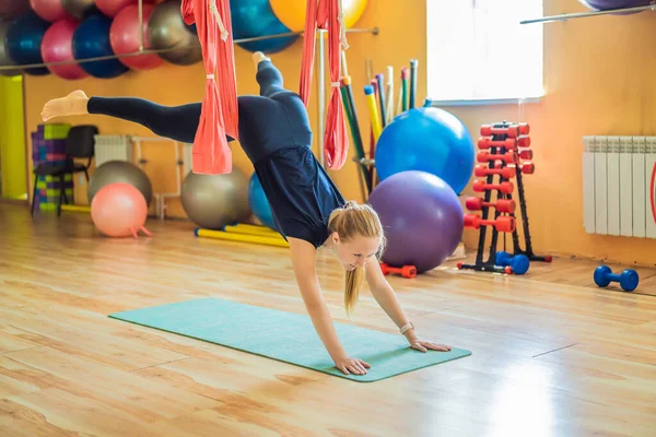 Genç ve güzel bir kadın spor salonunda hava yogası yapıyor. Yaşam biçimi