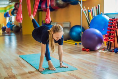 Genç ve güzel bir kadın spor salonunda hava yogası yapıyor. Yaşam biçimi