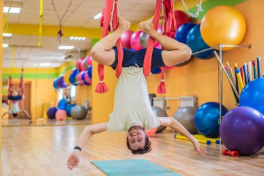 Spor salonunda hava yogası yapan genç bir adam. Yaşam biçimi