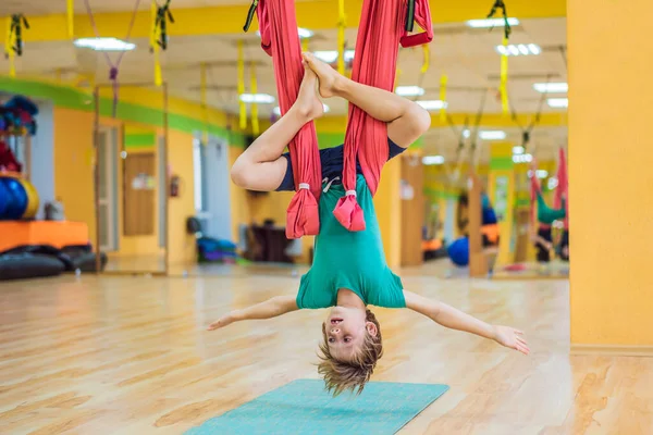 Young boy practicing aerial yoga in gym. Lifestyle. Kids yoga concept