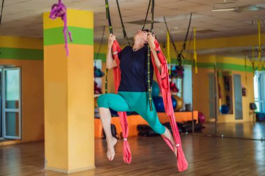 Yetişkin bir kadın stüdyoda hamakla anti-yerçekimi yogası yapıyor. Yaşam biçimi